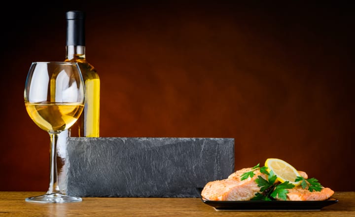 una mesa con vino blanco y un plato de pescado